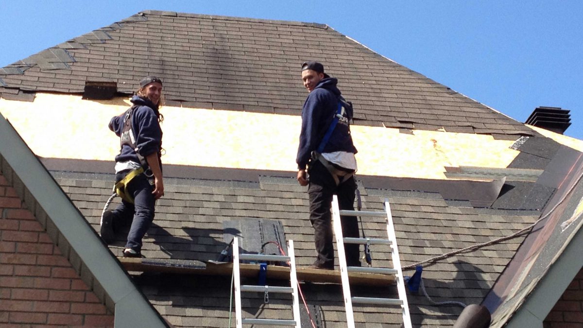 Roof replacement. Godfrey Roofing employees standing on pitch of roof.