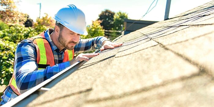 A,Man,With,Hard,Hat,Standing,On,Steps,Inspecting,House A man with hard hat standing on steps inspecting house roof for roof inspections