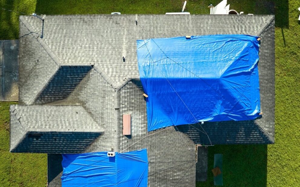 Residential Emergency Roof Repair. Aerial View Of Damaged In storm House Roof Covered.