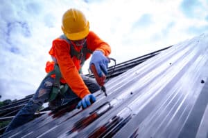 Roofer working on roof structure of building on construction site,Roofer using air or pneumatic nail gun and installing commercial roofing Metal Sheet on top new roof