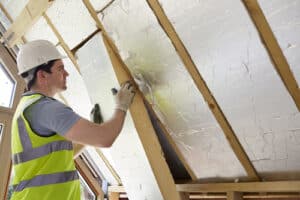 Builder Installing Insulating Board Into Roof Of House