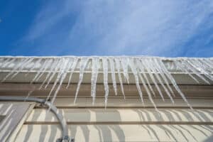 Roofing Problems. Frozen Gutters With Long Icicles Hanging From Ice Dams.