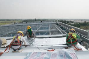 commercial roofing. Construction Workers Wearing Safety Harness And Safety Line Working On Commercial roof.