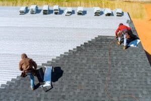 Roof Contractors. Roofing Contractors Aerial View In Worker Installing Roof Shingles.