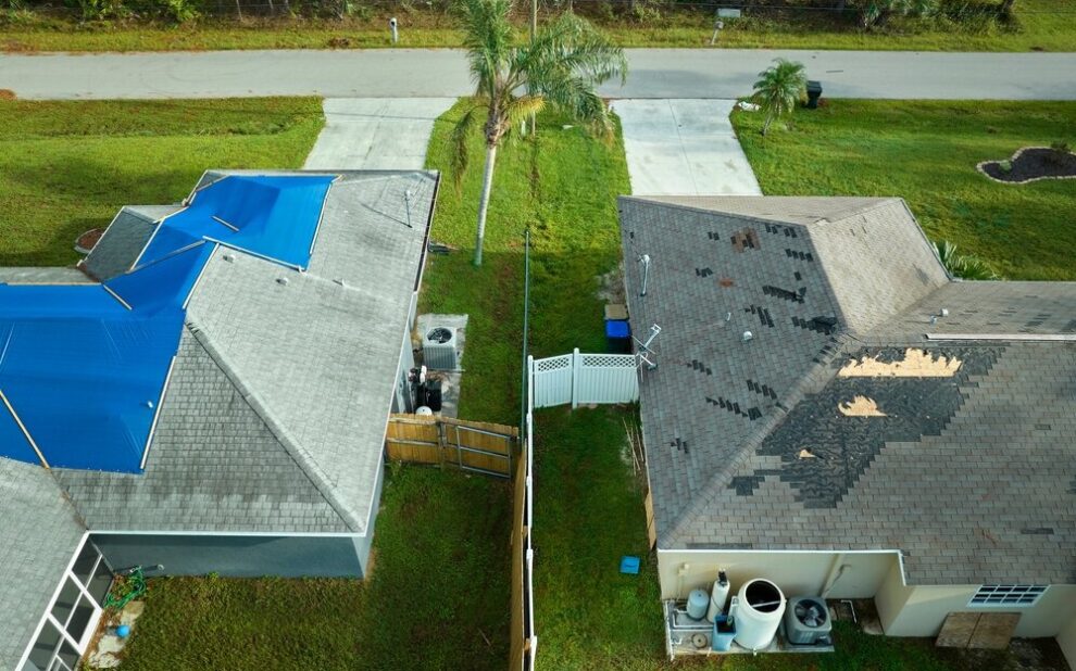 Roofing Contractors. Aerial View Of Damaged In Hurricane House Roof Covered.