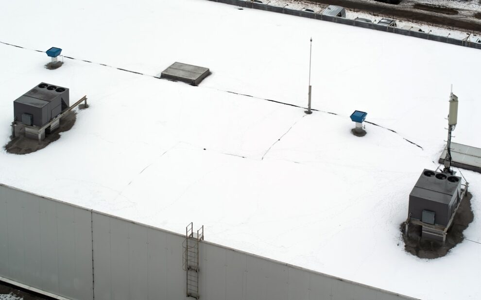 Commercial Roofing. Roof of a commercial building with a external units of the commercial air conditioning and ventilation systems, cellular antenna and lightning rod. Winter photo.