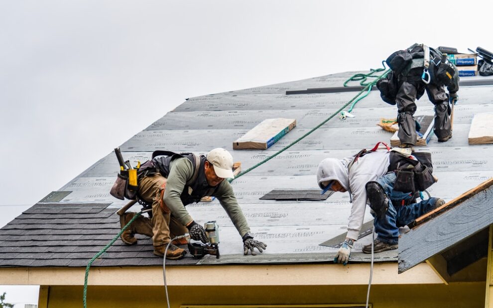 Winter Roof Repairs. Professionals repairing damage to roof from winter storm.
