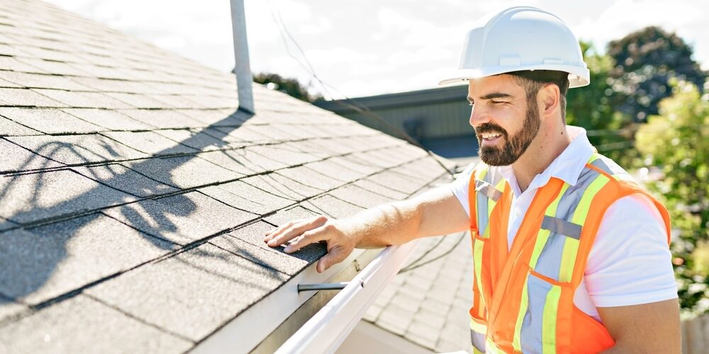 shutterstock_2046901877 (1) Why Trust Godfrey Roofing for A Professional Roof Inspection? A man in a hard hat, holding a clipboard, standing on the steps of an old rundown house.