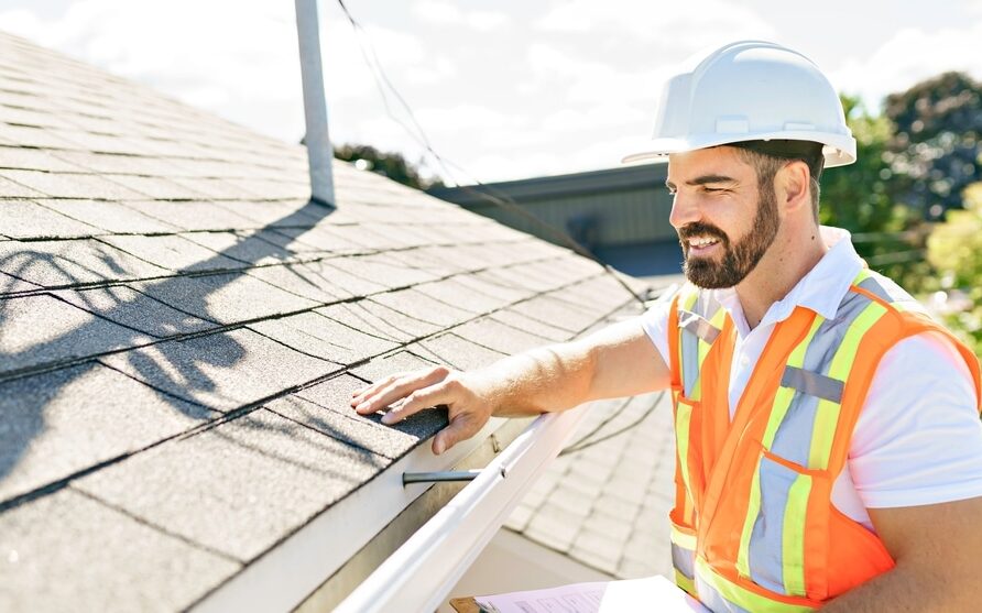 Why Trust Godfrey Roofing for A Professional Roof Inspection? A man in a hard hat, holding a clipboard, standing on the steps of an old rundown house.