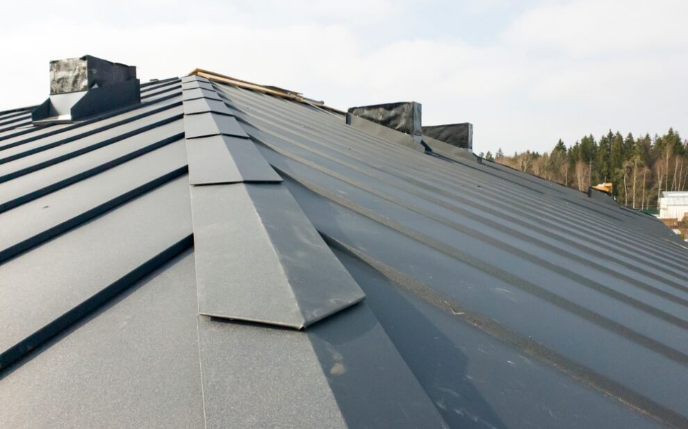 Metal Roofing System. close up view of grey folding roof and chimney on waterproofing layer of house under construction.