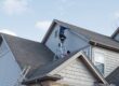 Godfrey Roofing Ottawa’s Premier Roofing Contractor. Roofers repairing damaged siding trim along multiple roof lines.