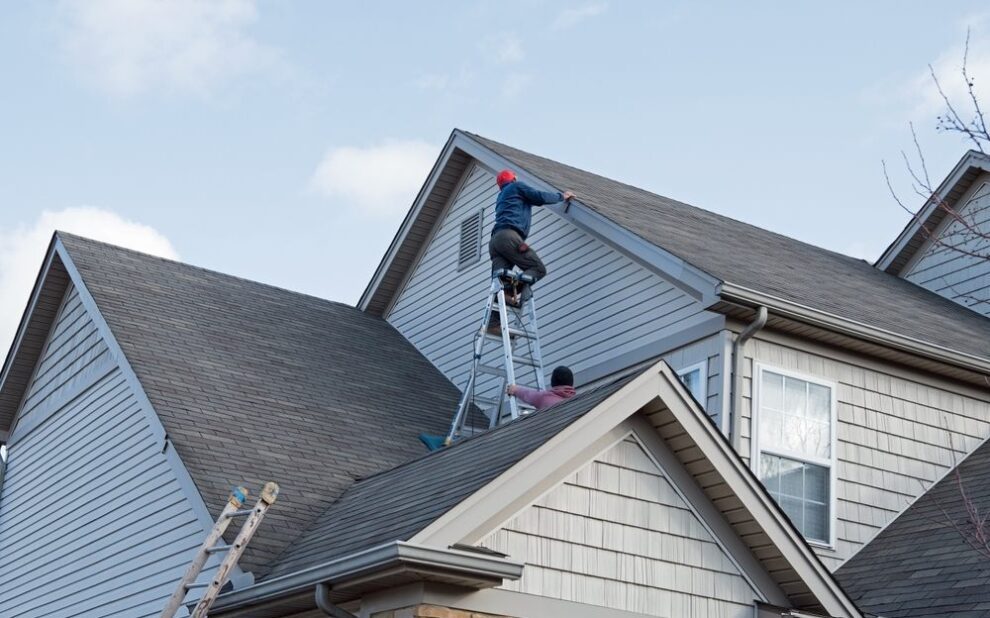 Godfrey Roofing Ottawa’s Premier Roofing Contractor. Roofers repairing damaged siding trim along multiple roof lines.