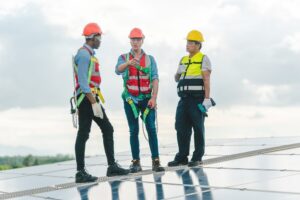 How Does Roof Asset Management Benefit Commercial Clients? Professional worker on roof structure of building factory. Professional talking with building rep for extending the life of their commercial roof.