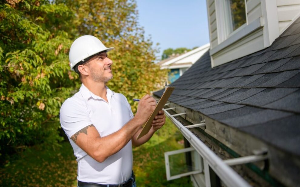When to Schedule Professional Roof Inspections for Your Property? A Man with a white hard hat holding a clipboard, inspect house roof.