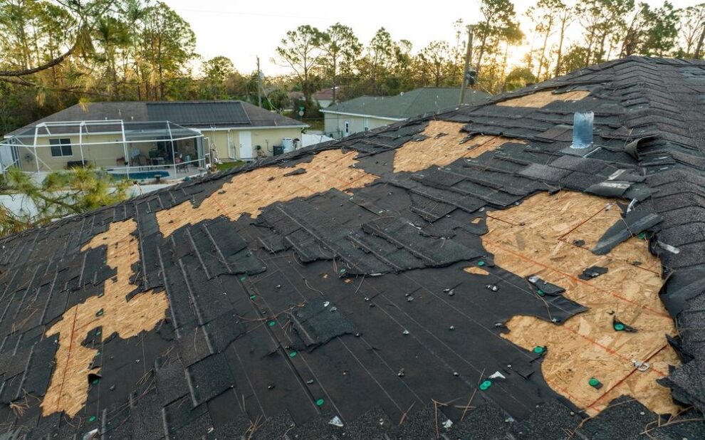 Spring Thaw & Your Roof: Why Melting Snow Can Lead to Critical Roof Repair. Ruined rooftop in need of repair. Wind damaged house roof with missing asphalt shingles.