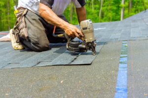 The Ottawa Homeowner's Guide to Long-Term Roof Health: Beyond the Spring Repair. A roofer worker installing new bitumen shingles on the roof used an air pneumatic nail gun. Repairing the roof.