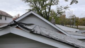 Spring Thaw & Your Roof: Why Melting Snow Can Lead to Critical Roof Repair. Damaged Roof With Curling Shingles and Water Damage Warning Signs.