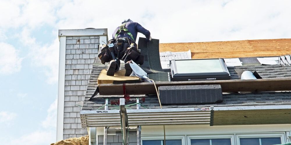 The Comprehensive Guide to Roof Replacement for Ottawa Homeowners in 2026. a roofer installs asphalt or bitumen shingles on a roof in a residential building.