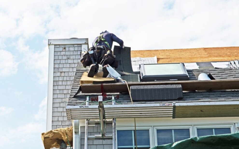 The Comprehensive Guide to Roof Replacement for Ottawa Homeowners in 2026. a roofer installs asphalt or bitumen shingles on a roof in a residential building.