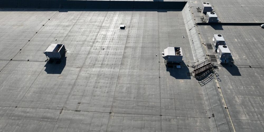 Commercial Roofing in Ottawa: A Strategic Guide for Property Resilience in 2026. A high angle view of a road surface, asphalt flooring and roof from above on a bright sunny day. Transportation is all around.