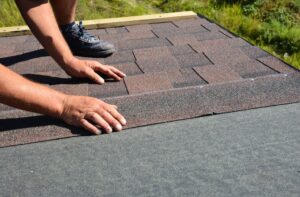 Roof Repair vs. Roof Replacement in Ottawa: How to Know What You Need. Roofing contractor lay asphalt shingles tiles on house rooftop. Asphalt shingles roofing construction, repair, installation, replace, renovation.