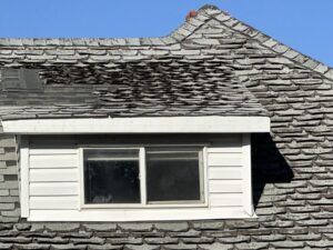 Roofing contractor lay asphalt shingles tiles on house rooftop. Residential asphalt shingle roof detail highlighting home maintenance, repair needs and exterior roofing condition.