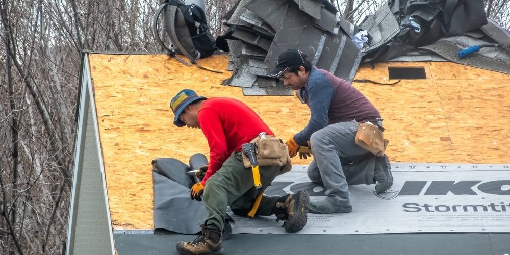 Ottawa Residential Roofing Upgrades: Local Trends & Solutions. Calgary, Alberta, Canada. Apr 10, 2025. Two construction workers are installing black underlayment on a plywood roof, preparing for shingles. Tools and bundles of shingles are visible.