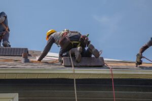 Exploring Career Opportunities: For Roofing Jobs in Ottawa. Construction workers wearing safety equipment install asphalt shingles on a residential roof in daylight. Ideal for roofing, home improvement, safety training, and construction industry visuals.