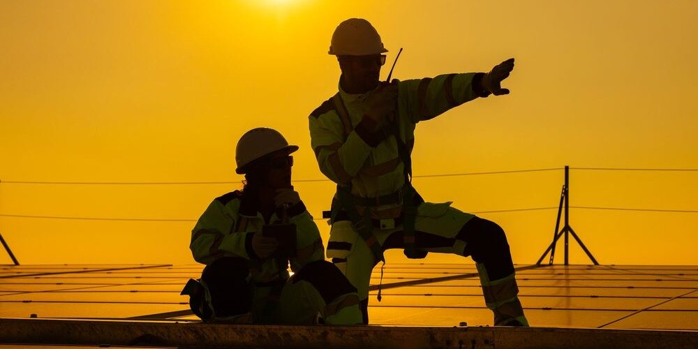 Exploring Career Opportunities: For Roofing Jobs in Ottawa. Two technicians sitting on rooftop at sunset discussing inspection results.