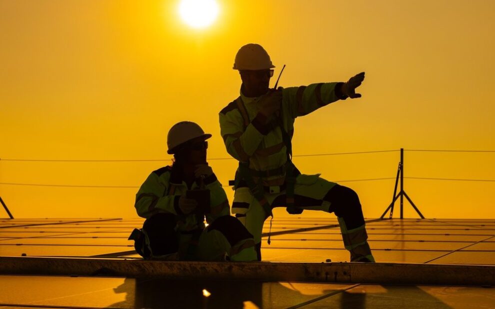 Exploring Career Opportunities: For Roofing Jobs in Ottawa. Two technicians sitting on rooftop at sunset discussing inspection results.