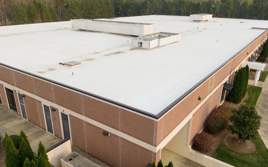 The Step-by-Step Process Commercial Roof Contractors Use for Large-Scale Roof Replacement. Professional aerial perspective of a modern commercial flat roof featuring a white TPO single-ply membrane installation. The image highlights the technical details of the roofing system, including the reflective surface designed for energy efficiency and UV resistance. The shot captures the symmetrical layout of the membrane sheets and the precision of the heat-welded seams, making it ideal for construction industry professionals, roofing contractors, and building inspectors. This high-resolution drone view emphasizes the scale and cleanliness of modern industrial infrastructure and sustainable building practices in 2026.